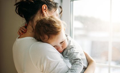 A mother holding a young toddler in her arms